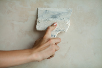 Man hand. Closeup of palette-knife or scraper and cement filling for house renovation construction.