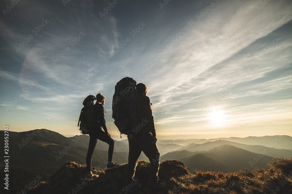 Wall mural the couple standing on a mountain with a picturesque sunset background