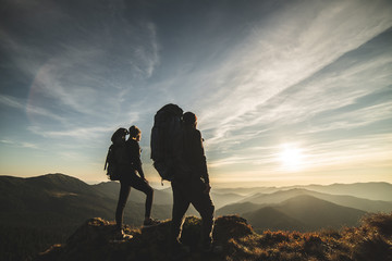 The couple standing on a mountain with a picturesque sunset background