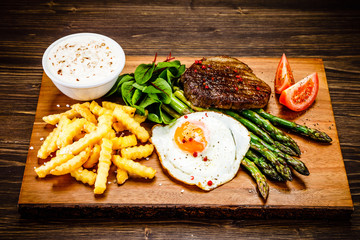 Grilled steak with asparagus, fried egg and french fries