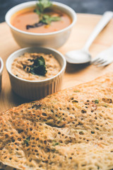 Onion rava masala dosa is a South Indian instant breakfast served with chutney and sambar over moody background. selective focus