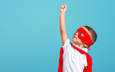 Little kid dressed like superhero on color baackground © luismolinero