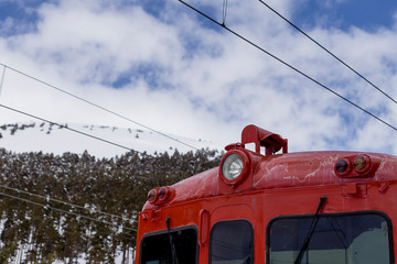 close up view of a red train locomotive in the mountains. blue and cloudy sky with snow. Winter season. Transport concept
