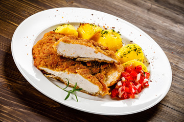 Fried pork chop, boiled potatoes and vegetable salad