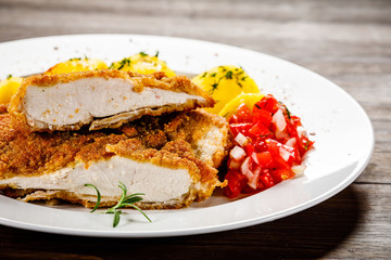 Fried pork chop, boiled potatoes and vegetable salad
