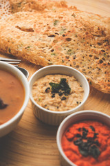 Onion rava masala dosa is a South Indian instant breakfast served with chutney and sambar over moody background. selective focus