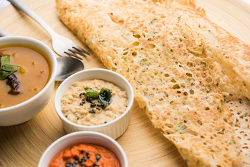 Onion rava masala dosa is a South Indian instant breakfast served with chutney and sambar over moody background. selective focus