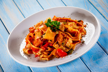Pasta with tomato sauce and vegtables on wooden table