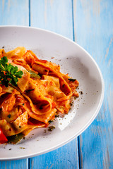 Pasta with tomato sauce and vegtables on wooden table