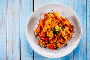 Pasta with tomato sauce and vegtables on wooden table