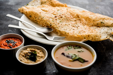 Onion rava masala dosa is a South Indian instant breakfast served with chutney and sambar over moody background. selective focus