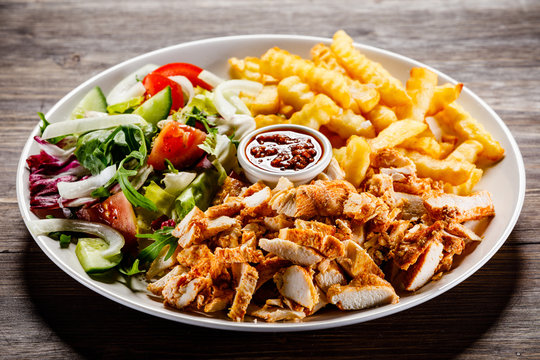 Kebab - grilled meat with french fries and vegetables on wooden background