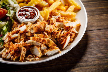 Kebab - grilled meat with french fries and vegetables on wooden background