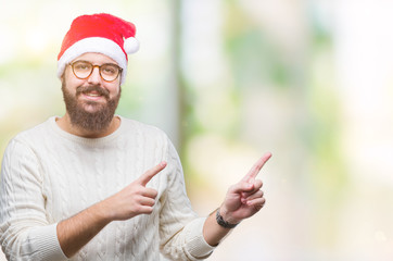 Fototapeta premium Young caucasian man wearing christmas hat and glasses over isolated background smiling and looking at the camera pointing with two hands and fingers to the side.