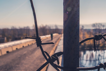 Lonely man behind barbed wire on the bridge