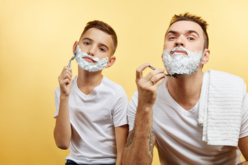bearded Father and son shaving on yellow background