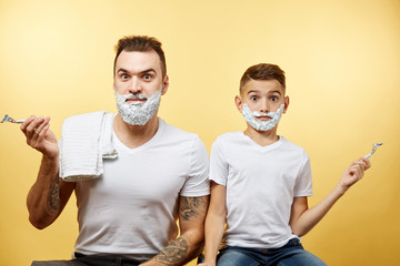 bearded Father and son shaving on yellow background