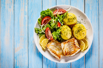 Fried fish with potatoes on wooden table