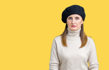 Middle age mature woman wearing winter sweater and beret over isolated background Relaxed with serious expression on face. Simple and natural looking at the camera.