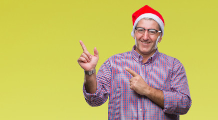Fototapeta na wymiar Handsome senior man wearing christmas hat over isolated background smiling and looking at the camera pointing with two hands and fingers to the side.