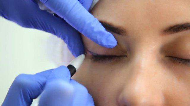 Permanent makeup. Permanent tattooing of eyebrows. Cosmetologist applying permanent make up on eyebrows- eyebrow tattoo.