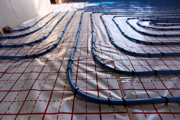 Laying blue pipes for floor heating at the construction site.