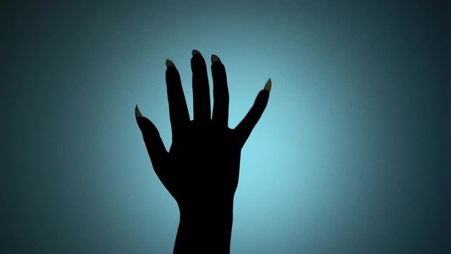 Hand of a creepy creature with sharp nails playfully scratches glass, threatens. Blood-chilling horror thriller shot