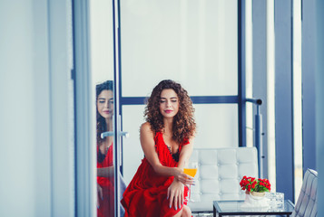 stylish beautiful woman with a glass of juice sits on the sofa