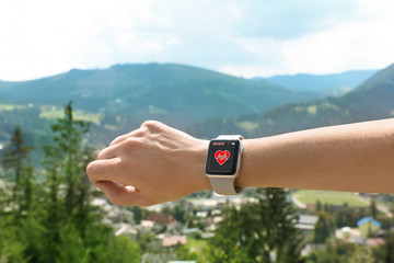 Woman using smart watch fitness app with heart rate monitor in mountains