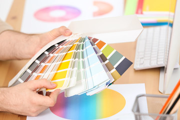 Designer with paint color palette samples at table, closeup