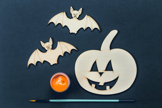 Do it yourself Halloween pumpkin and vampire bats wooden cut outs with paint and brush in flat lay style