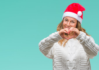 Middle age senior hispanic woman wearing christmas hat over isolated background smiling in love showing heart symbol and shape with hands. Romantic concept.