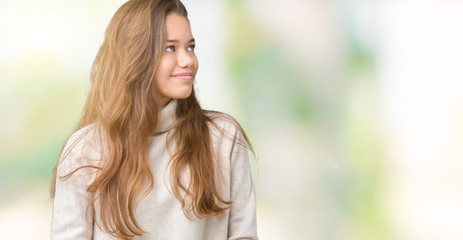Young beautiful brunette woman wearing turtleneck sweater over isolated background looking away to side with smile on face, natural expression. Laughing confident.