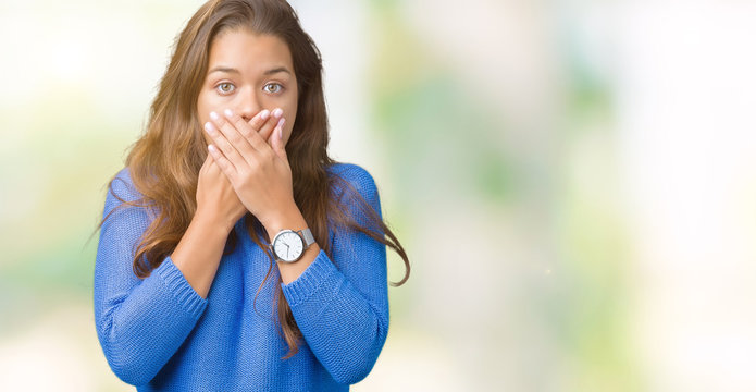 Young beautiful brunette woman wearing blue sweater over isolated background shocked covering mouth with hands for mistake. Secret concept.