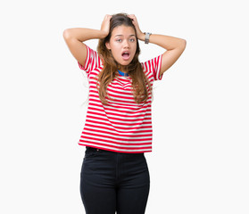 Obraz na płótnie Canvas Young beautiful brunette woman wearing stripes t-shirt over isolated background Crazy and scared with hands on head, afraid and surprised of shock with open mouth