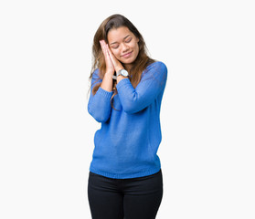 Young beautiful brunette woman wearing blue sweater over isolated background sleeping tired dreaming and posing with hands together while smiling with closed eyes.