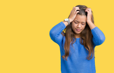 Young beautiful brunette woman wearing blue sweater over isolated background suffering from headache desperate and stressed because pain and migraine. Hands on head.