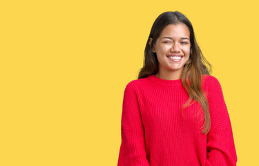 Fototapeta premium Young beautiful brunette woman wearing red winter sweater over isolated background winking looking at the camera with sexy expression, cheerful and happy face.