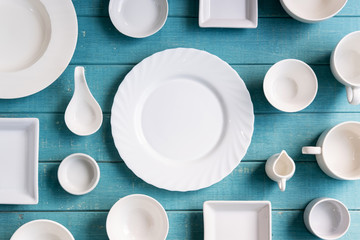 Various empty white plates and bowls on wooden background, Top view - obrazy, fototapety, plakaty