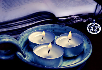 three candles, magic book and pentagram, like magic esoteric occult concept 