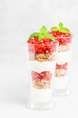 Pomegranate parfait - sweet organic layered dessert with granola flakes, yogurt and red ripe fruit seeds.