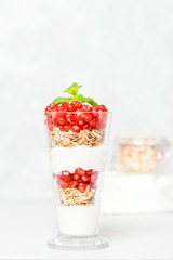 Pomegranate parfait - sweet organic layered dessert with granola flakes, yogurt and ripe fruit seeds.