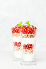 Pomegranate parfait - sweet organic layered dessert with granola flakes, yogurt and ripe fruit seeds.