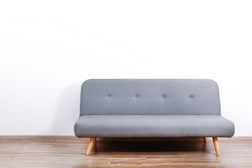 Minimalistic interior design concept. Grey textile sofa in spacious room of loft style apartment with wood textured laminated flooring. Background, copy space, close up.