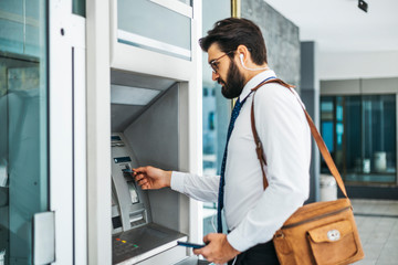 Fototapeta premium Businessman using card at an ATM