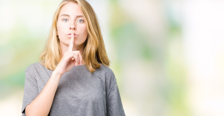 Fototapeta na wymiar Beautiful young woman wearing oversize casual t-shirt over isolated background asking to be quiet with finger on lips. Silence and secret concept.