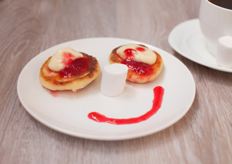 Summer cottage cheese pancakes on white plates on a table with jam, closeup, Smiling. Smile for sweet breakfast with love