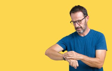 Handsome middle age hoary senior man wearin glasses over isolated background Checking the time on wrist watch, relaxed and confident