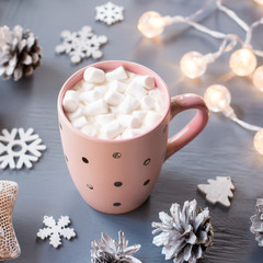 Obraz na płótnie Canvas Winter background with hot drink with marshmallows, Christmas lights, fir tree and decorations.