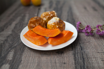 Homemade oven baked apples stuffed with pumpkin seeds and almond nuts in white plate closeup